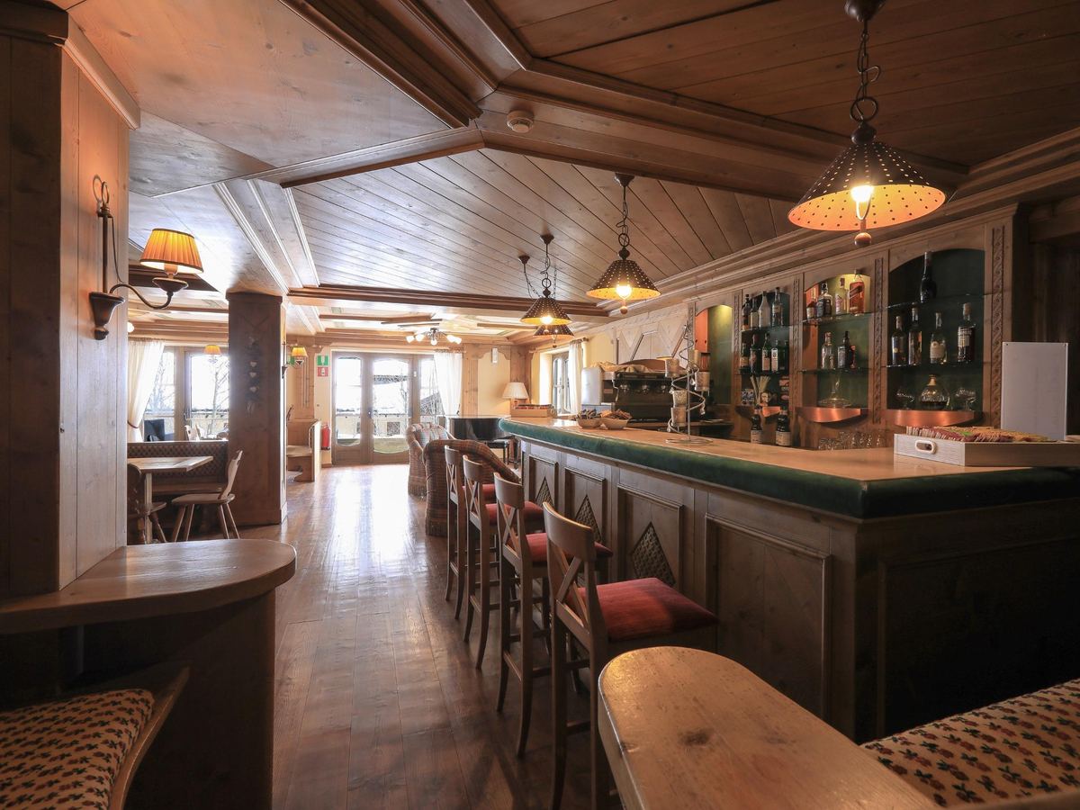 Bancone del bar in legno con bottiglie e sgabelli imbottiti