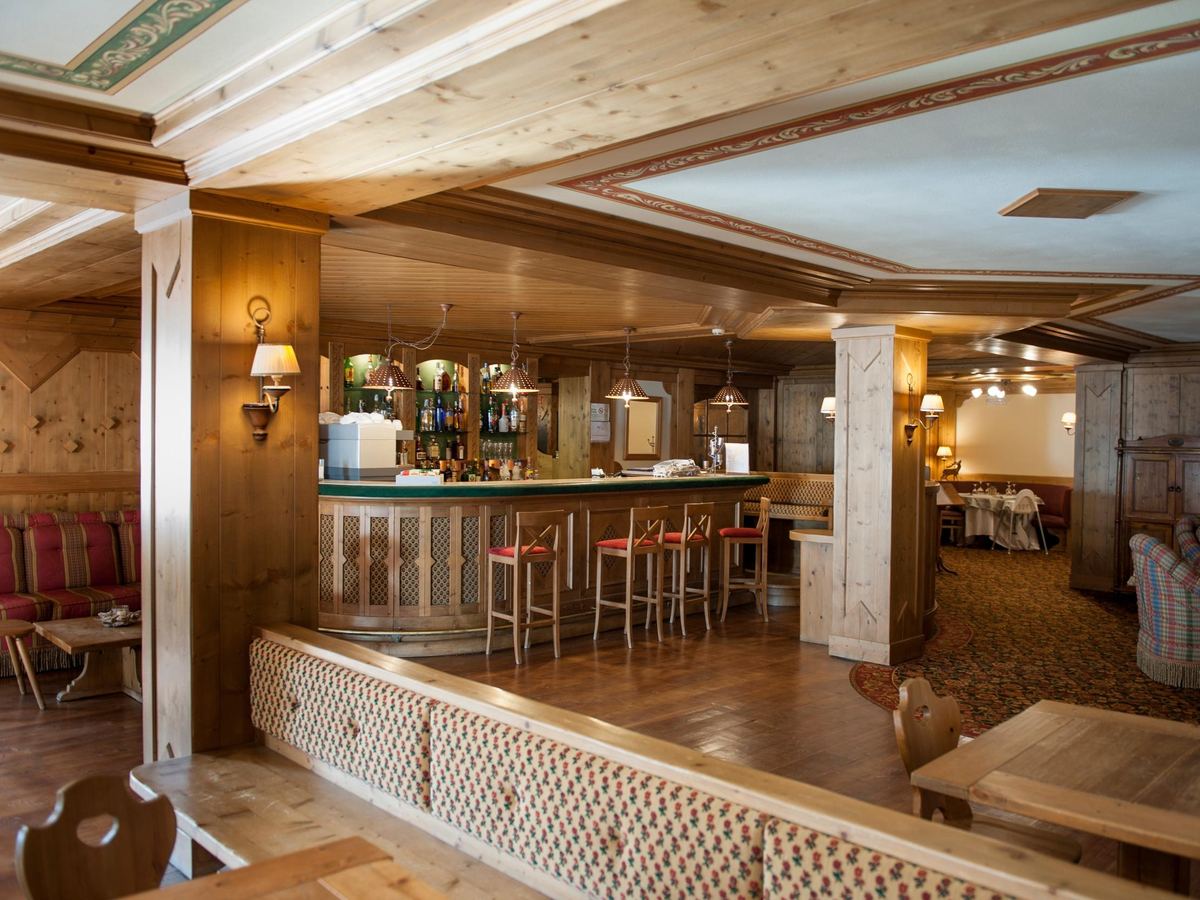 Bancone del bar dell'hotel visto dal salotto, con luci soffuse e sedute imbottite