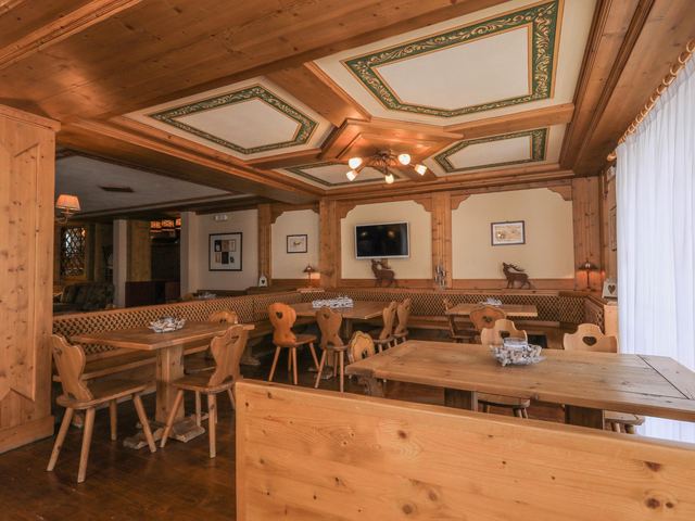 La Stube vista dall'ingresso, con tavoli in legno e soffitto decorato