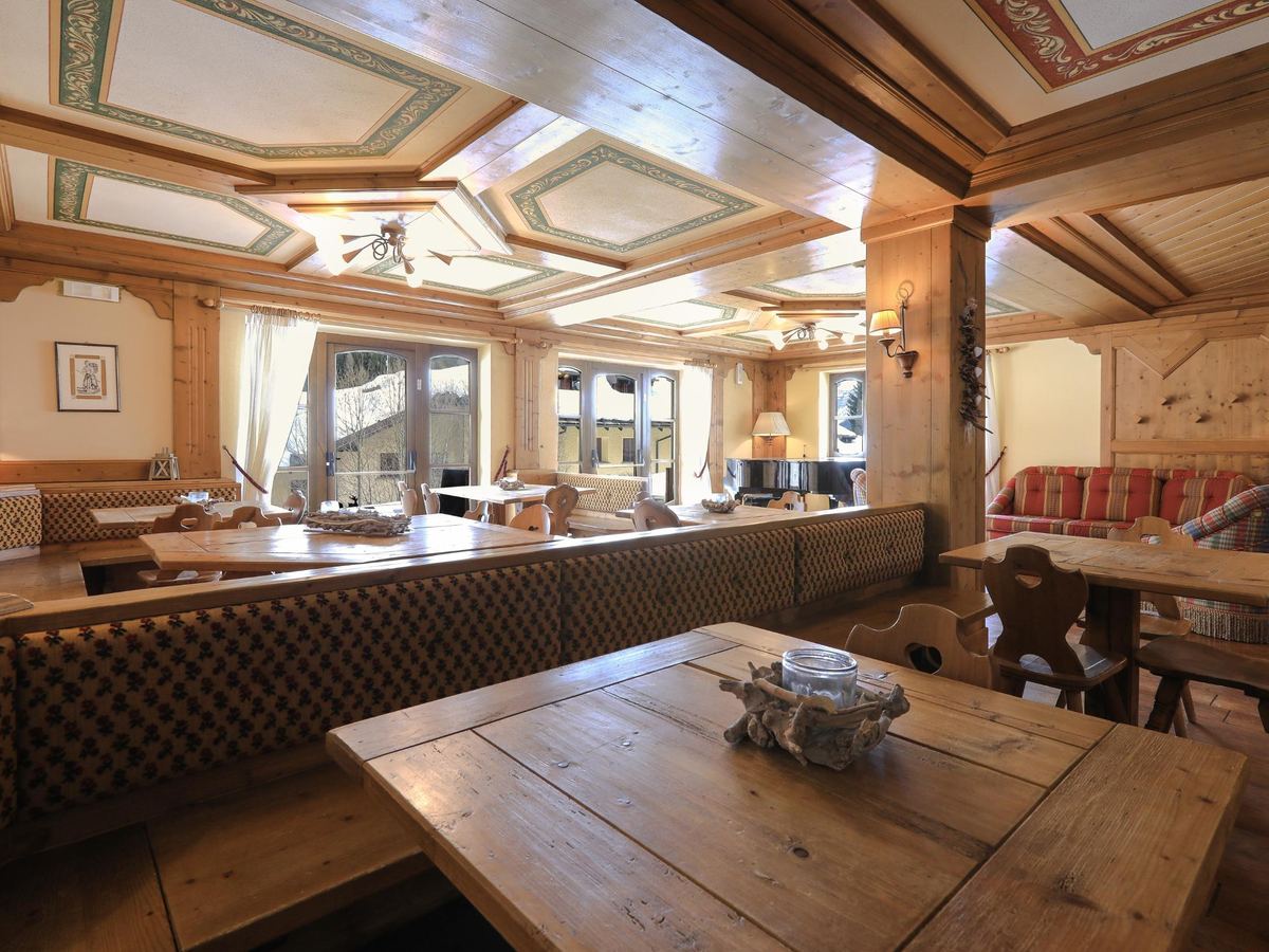 La Stube, sala rivestita in legno con tavoli e vista sul giardino innevato