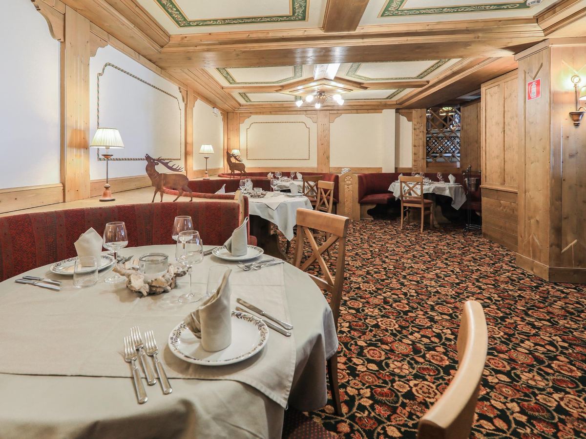 Sala ristorante di Hotel Perla con boiserie in legno, soffitto decorato e tavoli apparecchiati con eleganza