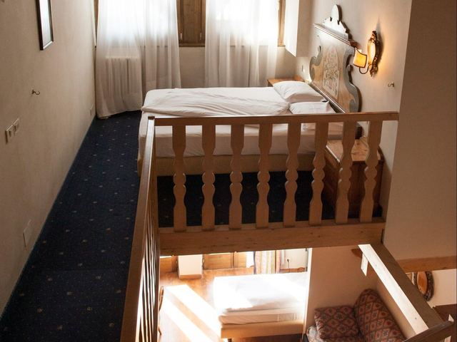 Suite Perla con soppalco in legno, letto matrimoniale su livello rialzato e ambiente living al piano inferiore