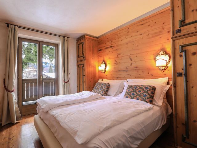 Camera Comfort di Hotel Perla con testata in legno, letto matrimoniale e luci calde