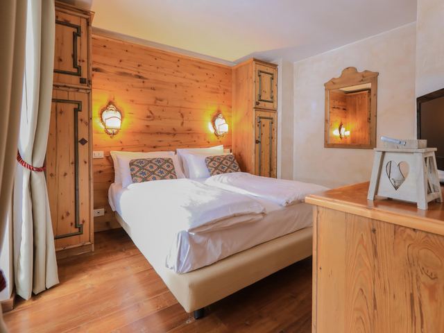 Camera con boiserie in legno di larice e letto matrimoniale